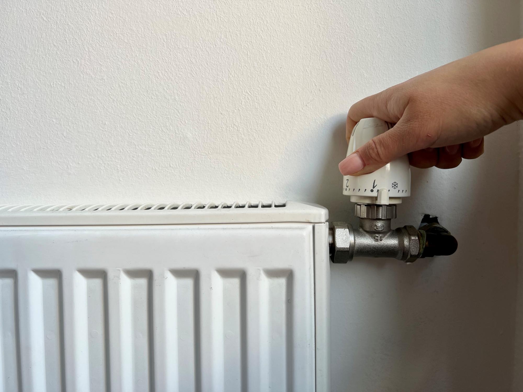 "Foto van iemand die aan de knop van de verwarming draait."
